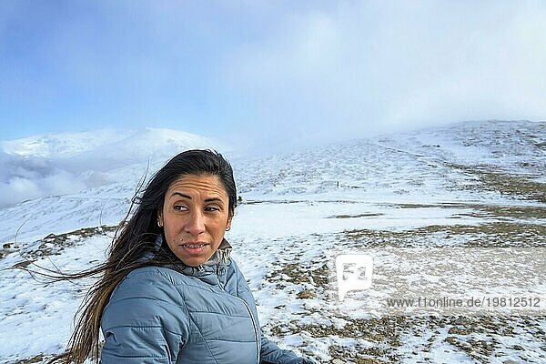 Latina mittleren Alters auf einem schneebedeckten Berg in einem Schneesturm