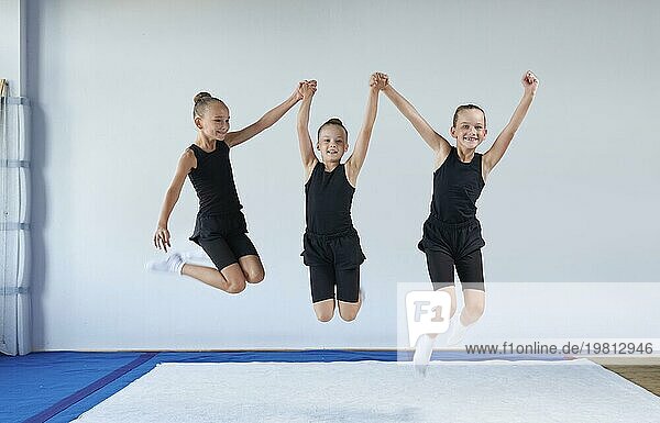 Gruppe von fröhlichen Kindern springen in der Turnhalle. Gymnastik Konzept. Gemischte Medien