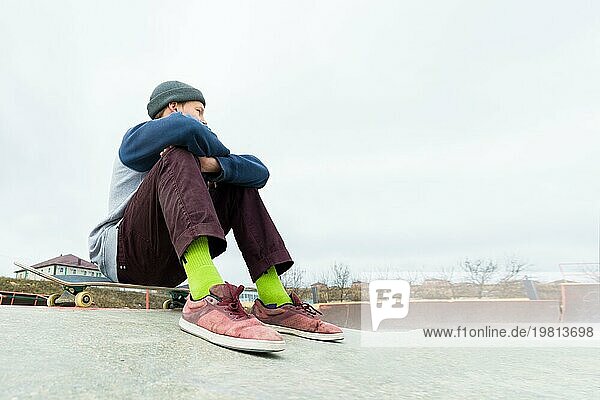 Ein Jugendlicher sitzt auf einem Skateboard im Park. Das Konzept der Freizeitbeschäftigung für Teenager in der Stadt