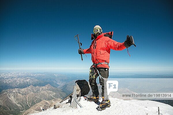 Profi Wanderer auf dem Gipfel des Felsens mit erhobenen Händen freut sich über den nächsten Sieg des Aufstiegs an einem sonnigen Nachmittag