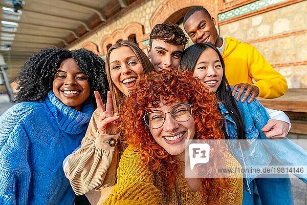 Verschiedene junge Freunde machen ein Selfie und lächeln und gestikulieren erfolgreich in einem städtischen Raum