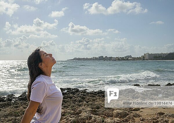 Entspannte Frau atmet frische Luft auf den Felsen am Mittelmeer