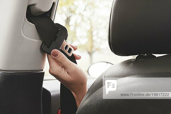 Die Hand einer Frau greift hinter ihren Sicherheitsgurt  um ihn zu schließen Das Konzept des sicheren Fahrens von Frauen im Auto