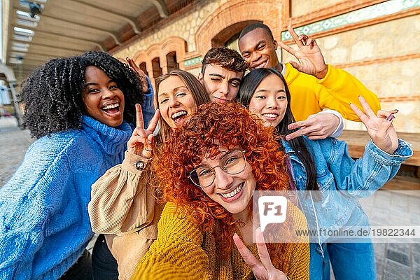 Junge unterschiedliche Freunde gestikulieren erfolgreich  während sie ein Selfie in der Stadt Straße