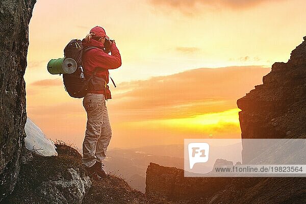 Mädchen Fotografin Reisende mit einem Rucksack in den Bergen fotografieren den Sonnenuntergang auf der Suche nach Abenteuer und schaffen Meisterwerk Fotos