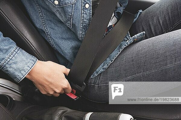 Frauenhände legen den Sicherheitsgurt im Auto an. Konzeption des sicheren Fahrens