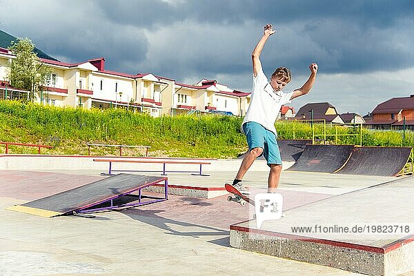 Junge Skateboarder in einem Skatepark  der einen Ollie Trick auf einem Skateboard vor einem Himmel und Gewitterwolken macht