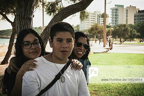 Fröhliche Gruppe junger Latinos  die im Freien in die Kamera lächeln  Familienporträt an einem sonnigen Tag im Freiluftpark