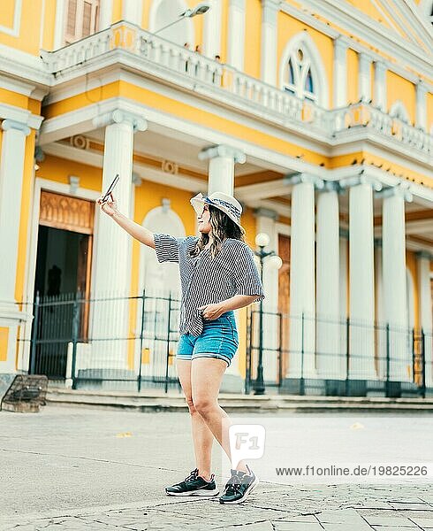 Schöne Touristin mit Hut macht ein Selfie in der Kathedrale von Granada. Junge Reisende Frau nimmt ein Selfie auf einem öffentlichen Platz