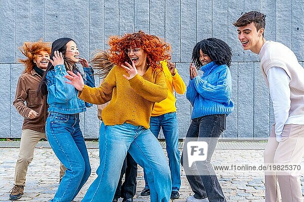 Frontalansicht eines glücklichen Mädchens  das mit einer Gruppe von Freunden in der Stadt tanzt