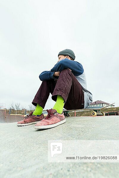 Ein Jugendlicher sitzt auf einem Skateboard im Park. Das Konzept der Freizeitbeschäftigung für Teenager in der Stadt