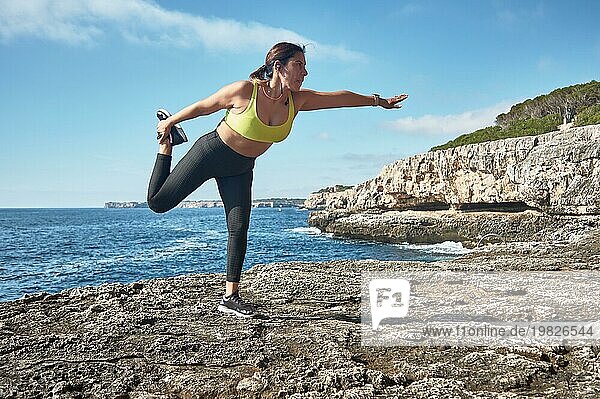 Lateinamerikanische Frau  mittleres Alter  trägt Sportkleidung  Training  macht körperliche Übungen  Planke  Sit ups  Kletterschritt  verbrennt Kalorien  hält sich fit  draußen am Meer  trägt Kopfhörer  Smartwatch