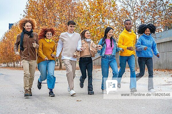 Weite Sicht auf verspielte multiethnische Freunde  die eine Straße entlanglaufen