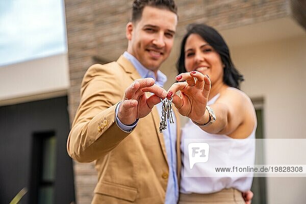 Frontalaufnahme eines glücklichen Paares  das die Schlüssel für ein neues Haus zeigt
