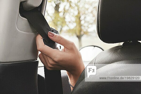 Die Hand einer Frau greift hinter ihren Sicherheitsgurt  um ihn zu schließen Das Konzept des sicheren Fahrens von Frauen im Auto