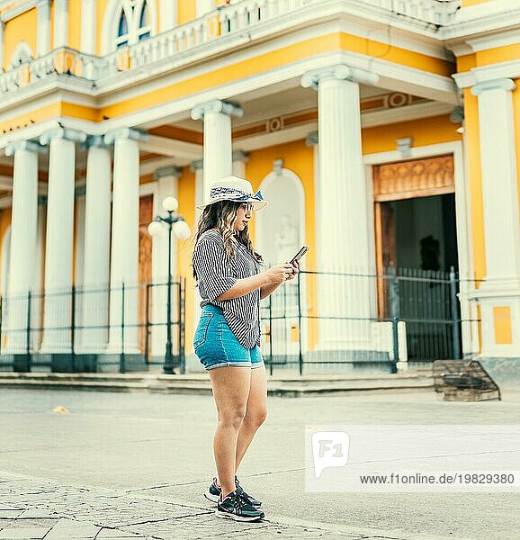Lifestyle von Touristen Frau SMS mit Telefon auf der Straße des Platzes. Schöne junge Reise Frau mit Hut mit Handy auf der Straße von Granada Nicaragua