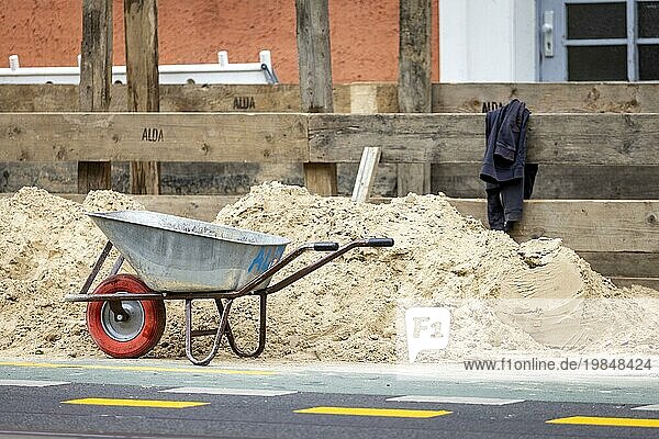 A wheelbarrow stands in front of a construction site on the pavement in Berlin  04/08/2023