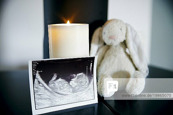 Symbolic photo: Staged photo on the subject of miscarriage. The ultrasound image of an unborn child stands next to a cuddly toy and a burning candle. Berlin  22/08/2023