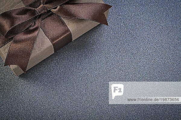 Eingepackt Geschenk mit braunen Knoten auf grauem Hintergrund Feiern Konzept