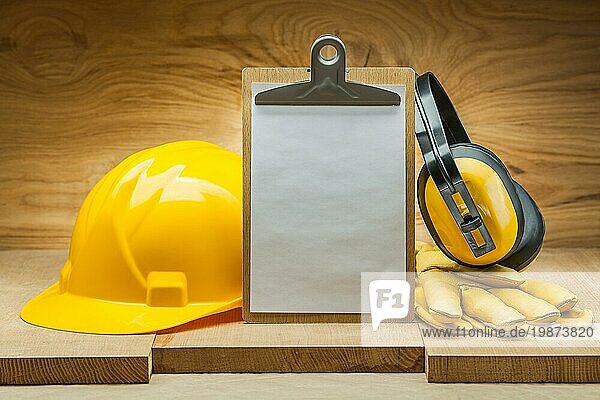 Baukonzept. Sicherheit der Arbeit. leeres Papierblatt in Zwischenablage gelber Helm Lederhandschuhe Kopfhörer