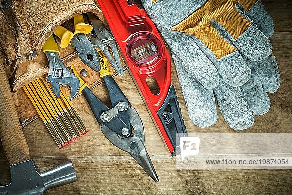 Werkzeuggürtel mit Schutzhandschuhen der Stufe Werkzeugbau auf Holzbrett
