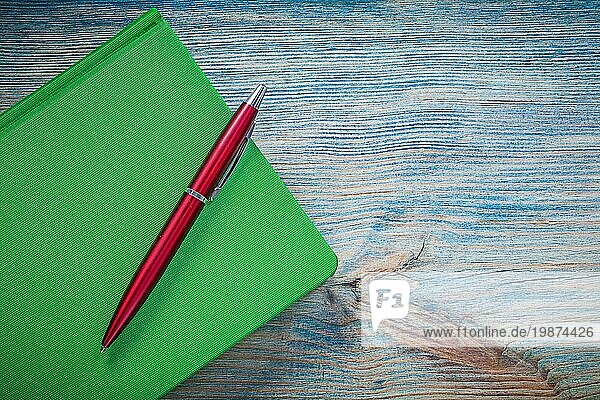 Geschlossenes grünes Notizbuch Kugelschreiber auf Holzbrett Bildungskonzept