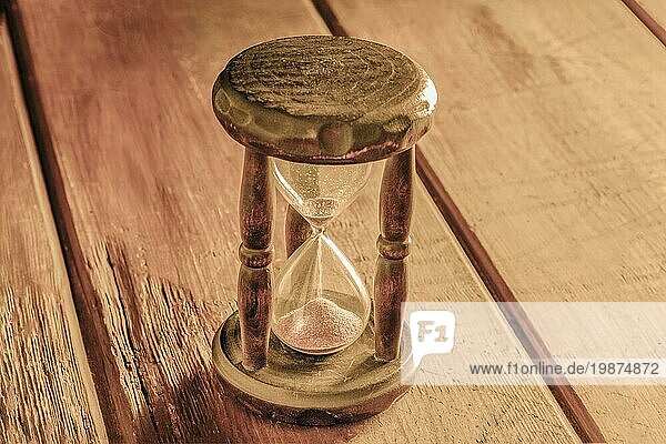 Zeit Konzept. Ein Vintage Sanduhr mit Sand fallen durch  auf einem rustikalen Hintergrund mit einem Platz für Text  getönten Bild