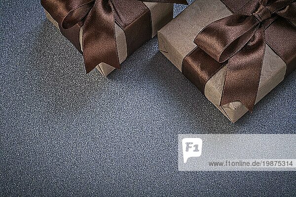 Geschenkboxen mit braunen Knoten auf grauem Hintergrund Feiern Konzept