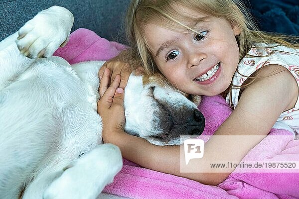 Happy Child kuscheln ein Beagle Hund bester Freund auf dem Sofa. Hund und Kinder Konzept