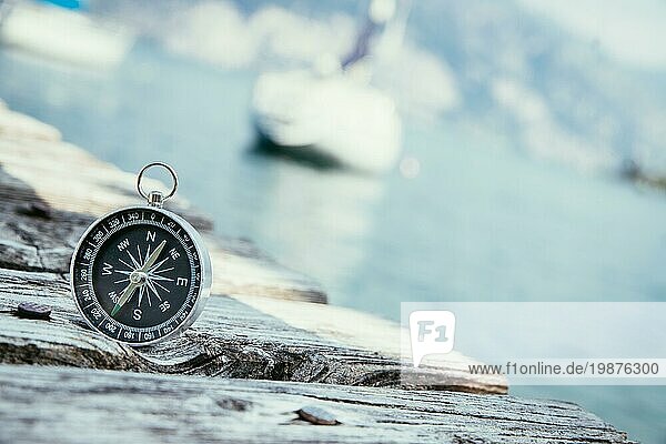 Kompass auf dem hölzernen Pier im Vordergrund  Segelboote im unscharfen Hintergrund