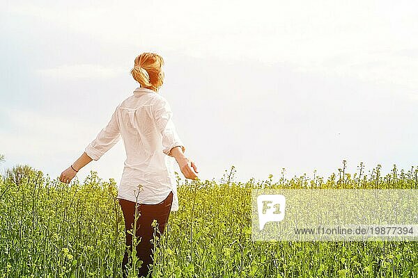 Die Schönheit eines Mädchens im Freien  das die Natur und die Freiheit genießt und das Leben genießt. Schönes Mädchen in einem weißen Hemd  spaziert auf einem Frühlingsfeld  die Sonne warmes Licht. Warmes grünes Bild