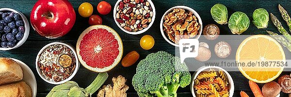 Gesundes veganes Lebensmittel Panorama. Top shot von Obst und Gemüse  Hülsenfrüchte  Pilze  Nüsse Ausgewogene Ernährung Konzept  auf einem dunklen Hintergrund
