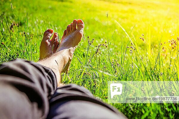 Beine eines jungen Mannes im grünen Sommergras  Sommerzeit