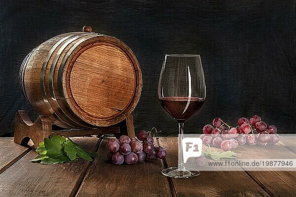 Ein Glas Rotwein mit einem Weinfass  Trauben und Weinblättern  auf einem dunklen rustikalen Hintergrund  Low Key Foto mit einem Platz für Text