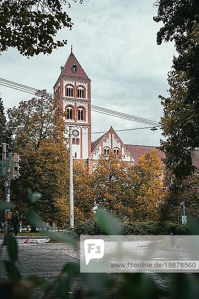 Blick auf eine Kirche mit rotem Ziegeldach und Glockenturm umgeben von herbstlichen Bäumen  Stuttgart  Deutschland  Europa
