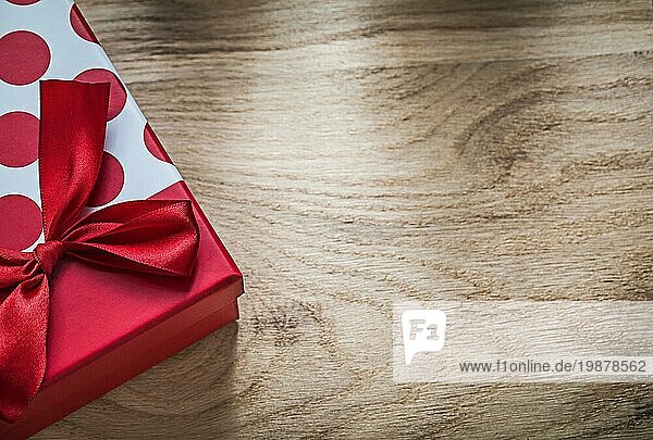 Verpackte Geschenkbox mit rotem Knoten auf Holzbrett Ferienkonzept