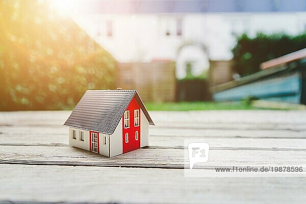 Rotes Hausmodell auf dem Boden  im Freien. Konzept für neues Haus  Grundstück und Anwesen