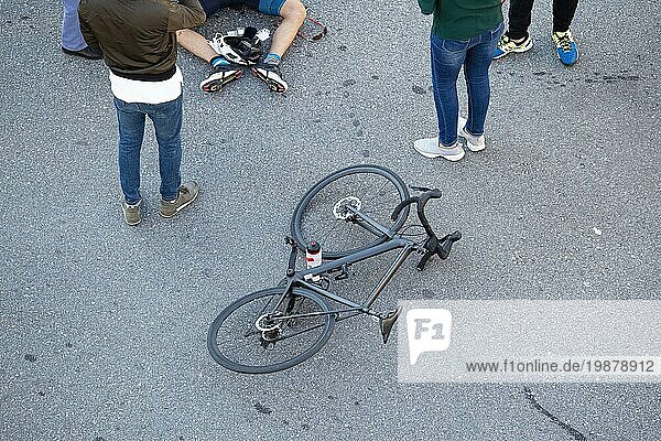 Fahrradunfall auf der Straße Szene mit Radfahrer und Fahrrad auf dem Asphalt  umgeben von Menschen  nachdem sie von einem Fahrzeug angefahren wurden