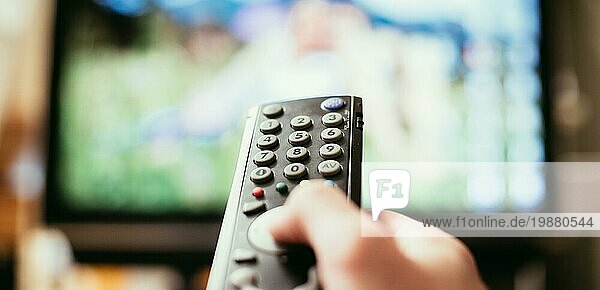 TV Fernbedienung im Vordergrund  Fernseher im unscharfen Hintergrund. Filmabend mit Vod Streaming