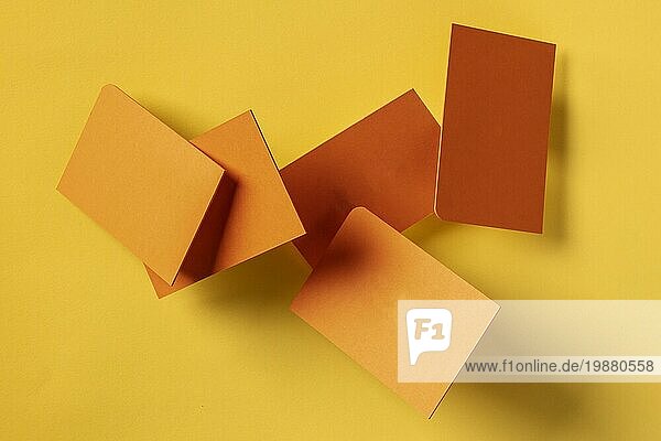 Dicke orangefarbene Visitenkarten mit abgerundeten Ecken  die auf einem gelben Papierhintergrund fliegen  eine Vorlage für eine kreative Designpräsentation