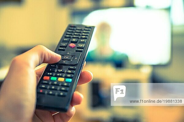 TV Fernbedienung im Vordergrund  Fernseher im unscharfen Hintergrund