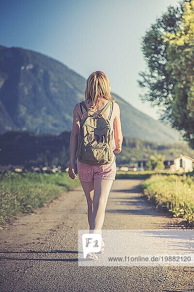 Junges Mädchen im Overall mit Rucksack macht einen Spaziergang  Sommerzeit