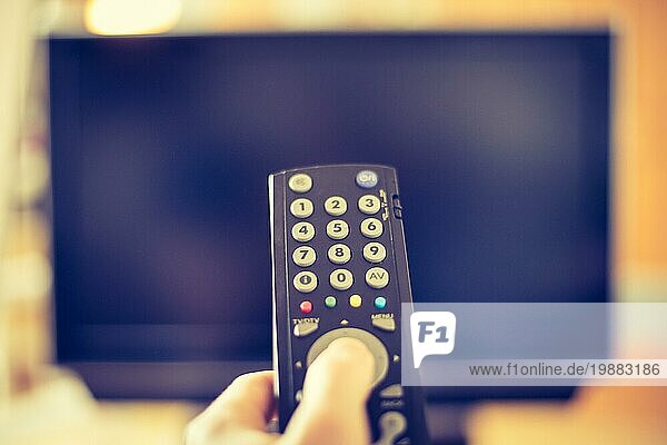 TV Fernbedienung im Vordergrund  Fernseher im unscharfen Hintergrund