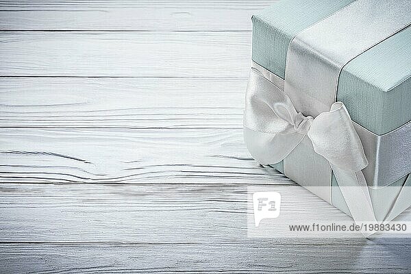 Blaue Geschenkbox mit weißem Knoten auf Holzbrett Feiern Konzept