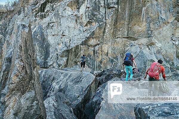 Bergsteiger bereiten sich auf den Aufstieg vor. Drei männliche und weibliche Personen gehen auf den Felsen. Extremer Outdoor Sport