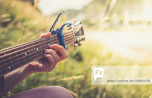 Nahaufnahme einer Westerngitarre  die im Freien an einem Fluss gespielt wird  Sommerzeit