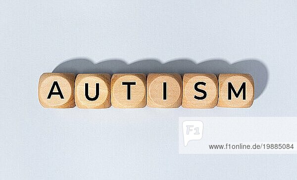 Autismus Wort auf Holzblock vorgrauem Hintergrund