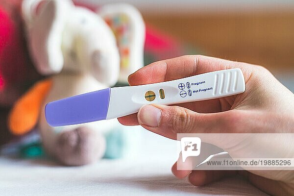 Frau Hand hält Schwangerschaftstest  Ergebnis ist schwanger