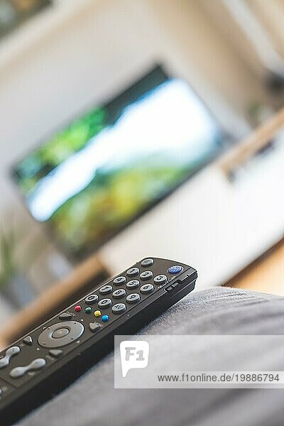 TV Fernbedienung im Vordergrund  Fernseher im unscharfen Hintergrund. Streaming