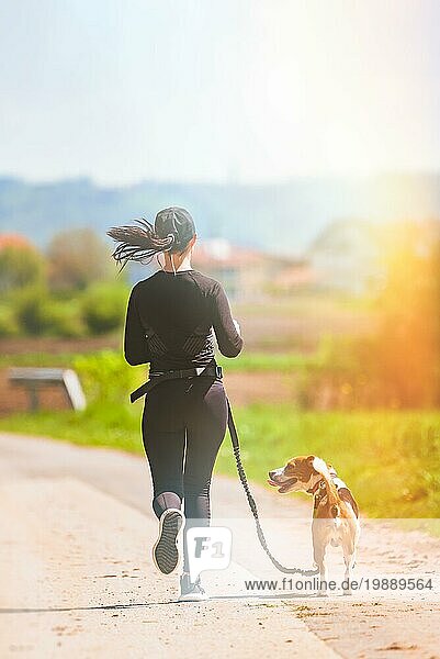 Mädchen läuft mit Hund draußen in der Natur auf einer Landstraße Sonniger Tag auf dem Lande mit Beagle Hund
